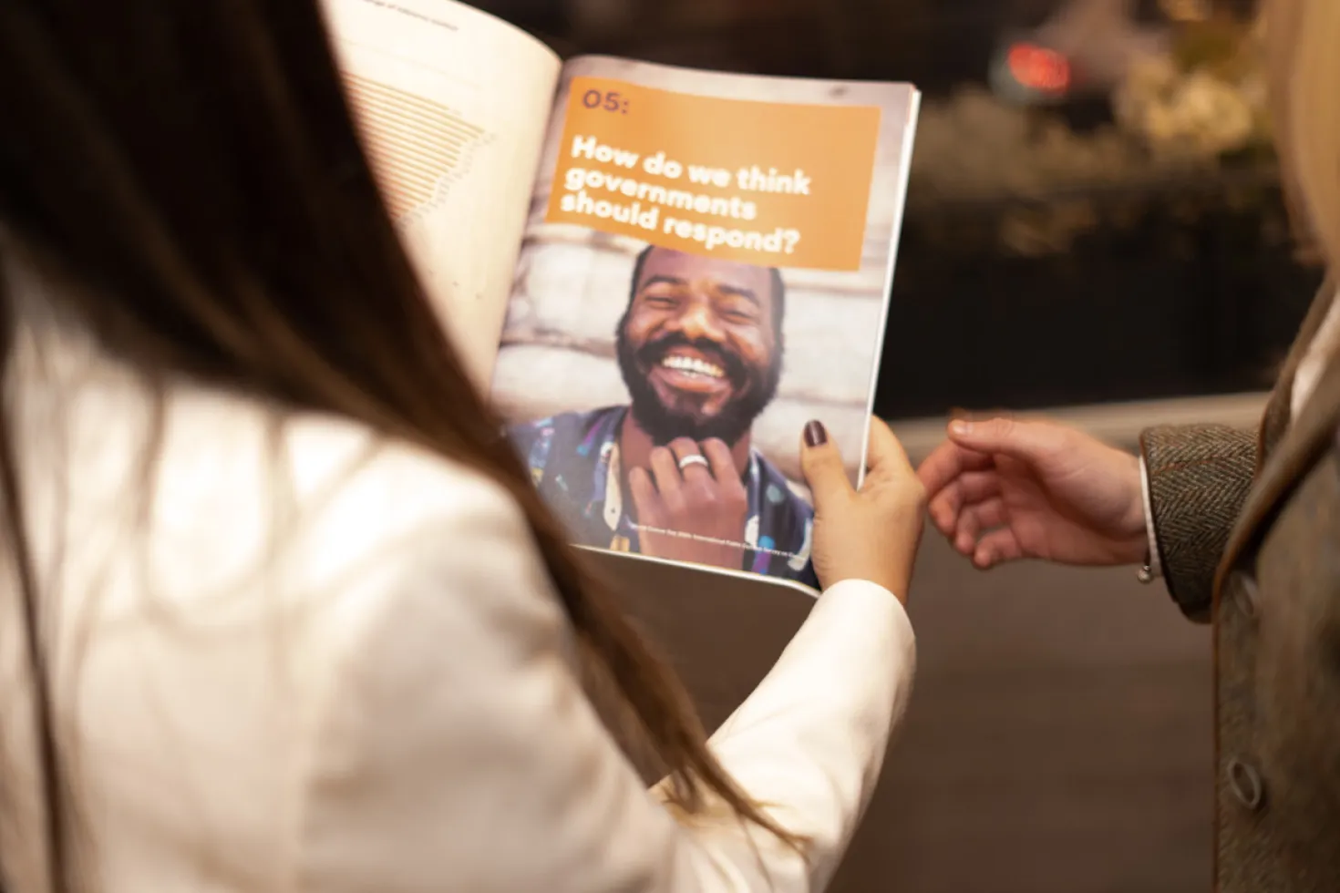 Woman holding a publication open with the title "How do we think the governments should respond?"