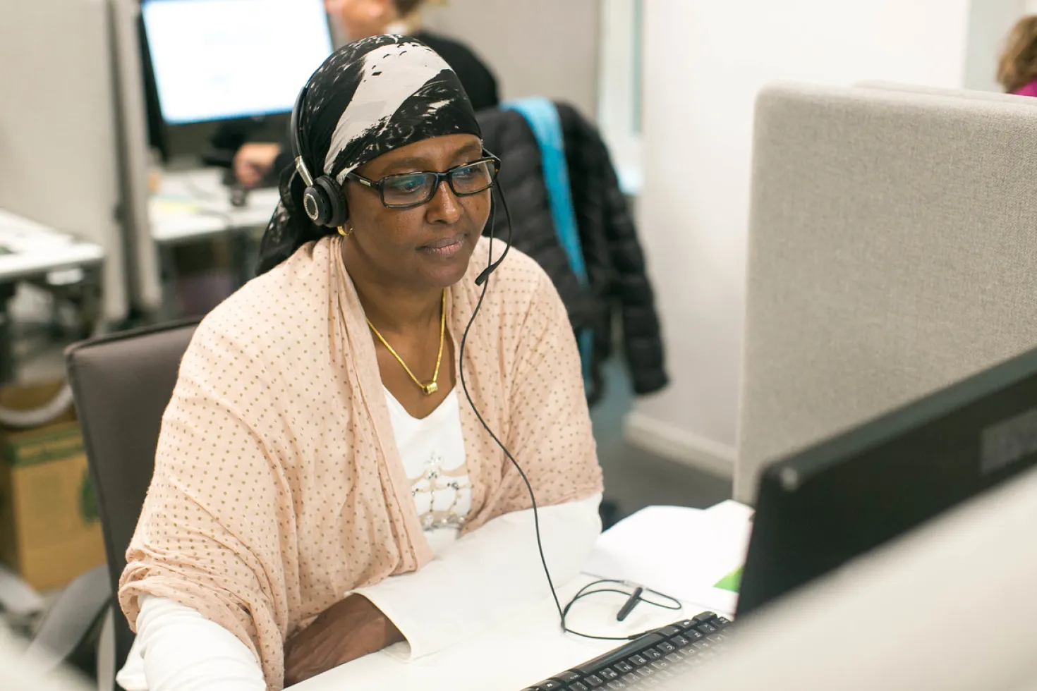 woman with headset looking at her screen computer