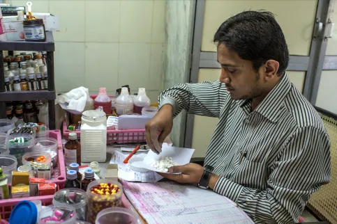 Man sitting at a desk weighing out medication