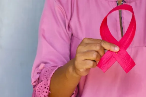 Woman dressed in pink holding a pink ribbon, symbolising breast cancer awareness month