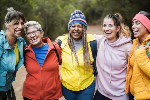 The differences in how cancer affects women to men is wide-ranging, from biological and medical effects of the disease and treatments to psychosocial and financial well-being, exposure to cancer risk factors and missed opportunities for cancer prevention. A group of women of different ages and ethnicities with arms over shoulders and smiling