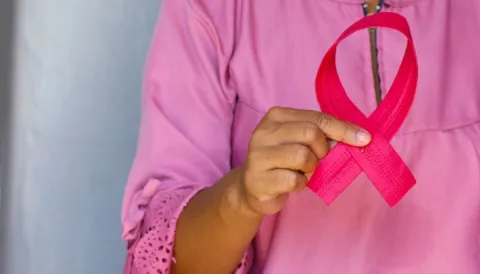 Late diagnosis and low survival rates constitute a common challenge faced by breast cancer organisations in low-income settings around the world. Woman dressed in pink holding a pink ribbon, symbolising breast cancer awareness month
