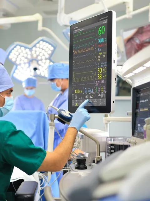 A male nurse checks a screen during a surgery